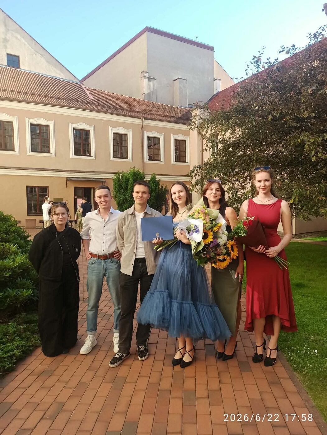 Urtė celebrating her graduation with friends and flowers