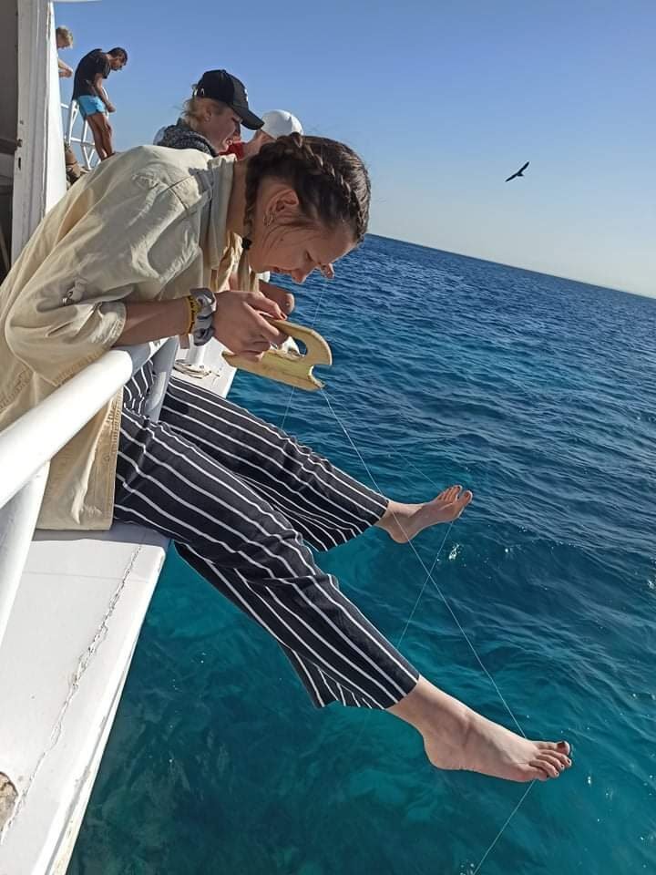 Urtė leaning off a boat over the sea